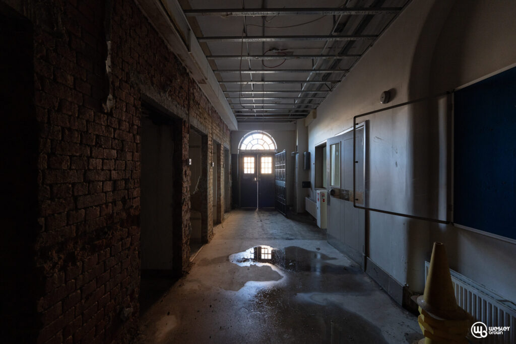 Broadmoore Hospital_32psd copy Dimly lit corridor with brick walls and arched window