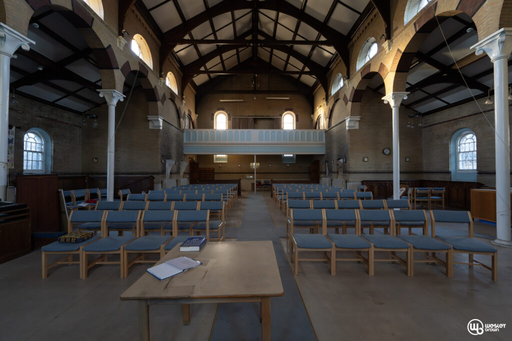 Broadmoore Hospital_41 copy Interior of a historic church with wooden benches and high arched ceiling.